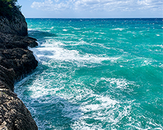 picture of ocean waves up against a cliff side 